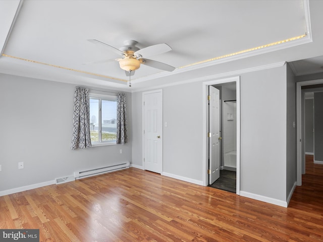 unfurnished bedroom with ensuite bathroom, a tray ceiling, ceiling fan, crown molding, and wood-type flooring