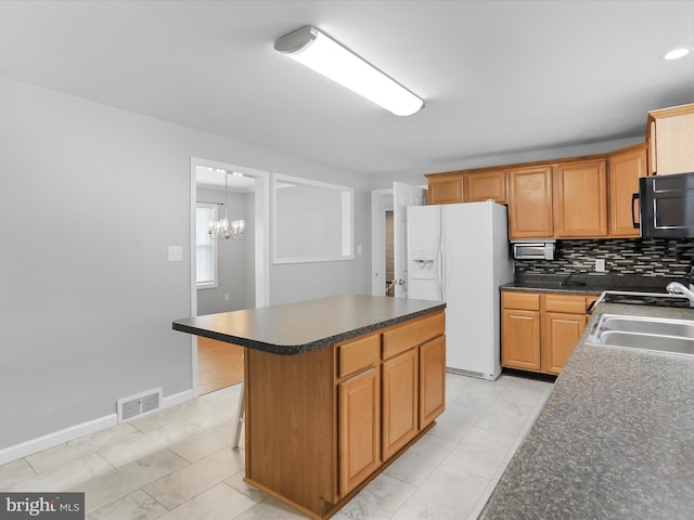 kitchen with backsplash, sink, white fridge with ice dispenser, a kitchen island, and a chandelier