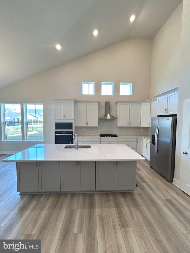 kitchen with white cabinets, wall chimney exhaust hood, a spacious island, and stainless steel refrigerator with ice dispenser