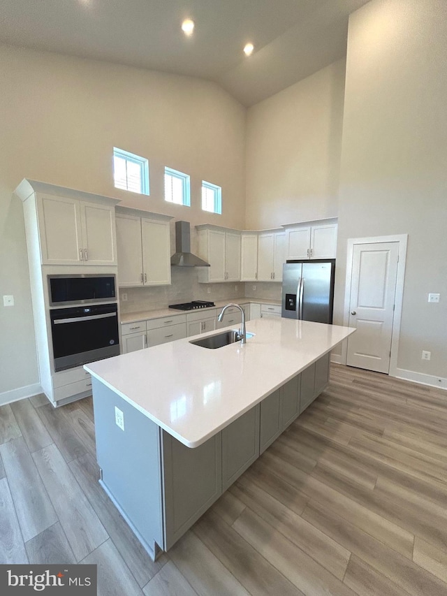 kitchen featuring white cabinets, sink, wall chimney range hood, and stainless steel appliances