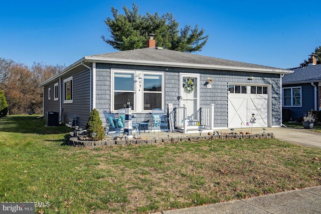 view of front of home featuring cooling unit, a garage, and a front lawn