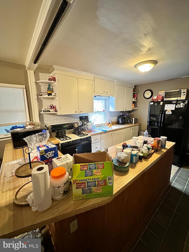 kitchen with black appliances, backsplash, cream cabinetry, and dark tile patterned flooring