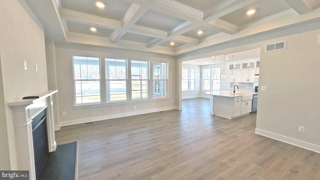 living room with beamed ceiling, sink, dark hardwood / wood-style floors, ornamental molding, and coffered ceiling