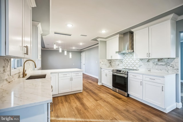 kitchen with white cabinets, wall chimney range hood, crown molding, stainless steel electric range oven, and decorative light fixtures