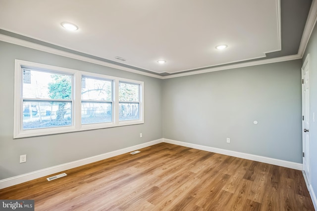 empty room featuring light wood-type flooring and ornamental molding