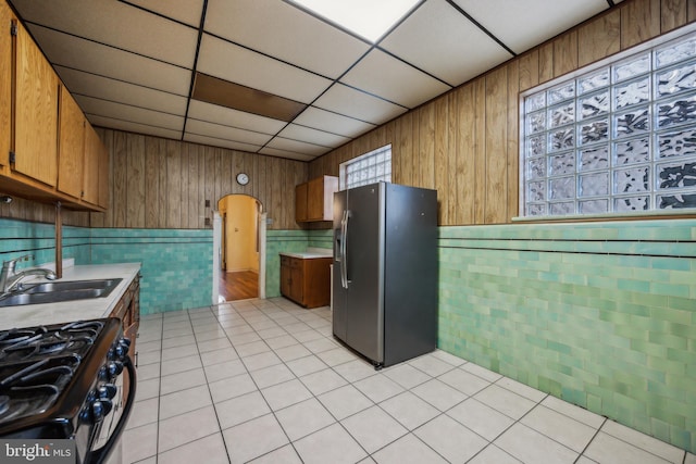 kitchen with light tile patterned floors, stainless steel appliances, a drop ceiling, and sink