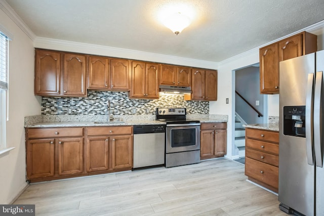 kitchen with crown molding, sink, light wood-type flooring, tasteful backsplash, and stainless steel appliances