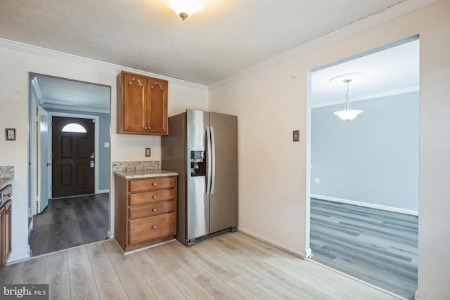 kitchen featuring pendant lighting, crown molding, a textured ceiling, light hardwood / wood-style floors, and stainless steel fridge with ice dispenser