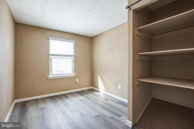 empty room with light hardwood / wood-style flooring and a textured ceiling