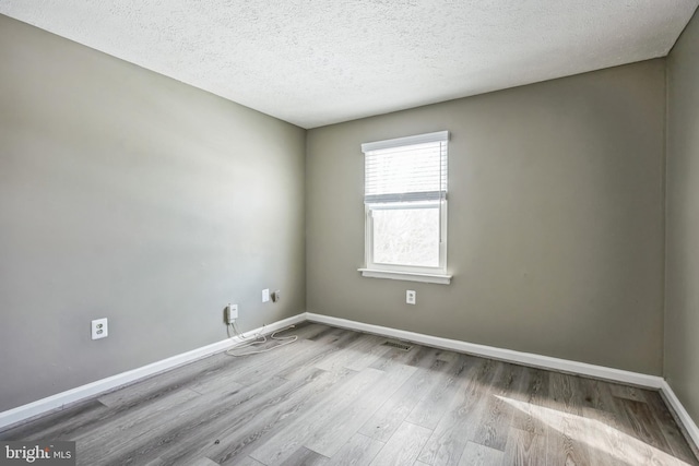 unfurnished room with light hardwood / wood-style flooring and a textured ceiling