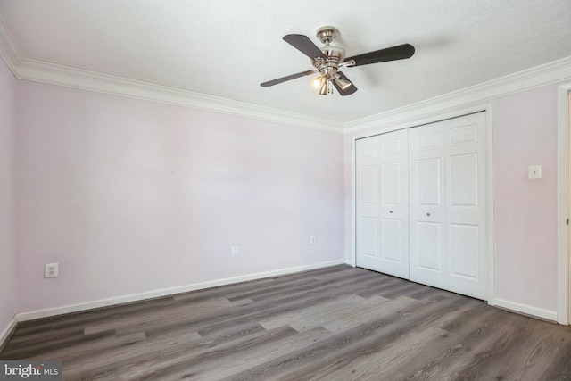 unfurnished bedroom featuring ceiling fan, dark hardwood / wood-style floors, ornamental molding, and a closet