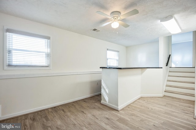 spare room with ceiling fan, light wood-type flooring, and a textured ceiling