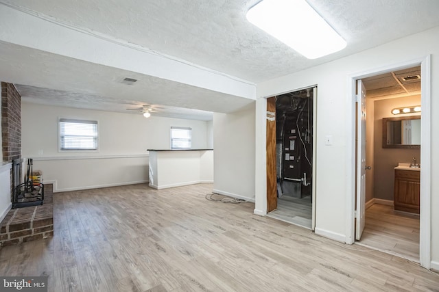 unfurnished living room with ceiling fan, sink, and light hardwood / wood-style flooring