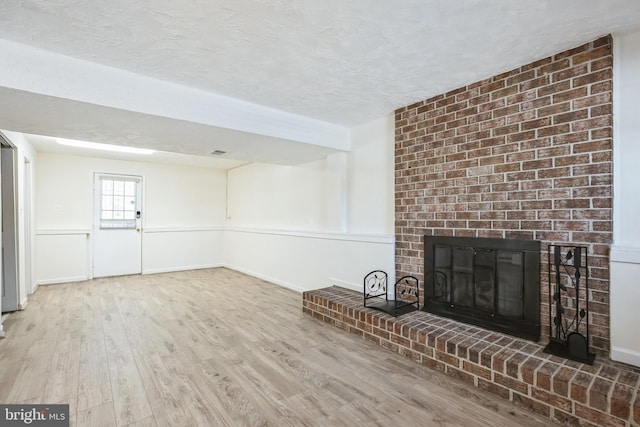 unfurnished living room featuring a fireplace, a textured ceiling, and hardwood / wood-style flooring