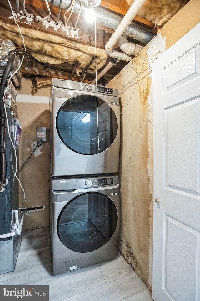 clothes washing area with light wood-type flooring and stacked washing maching and dryer