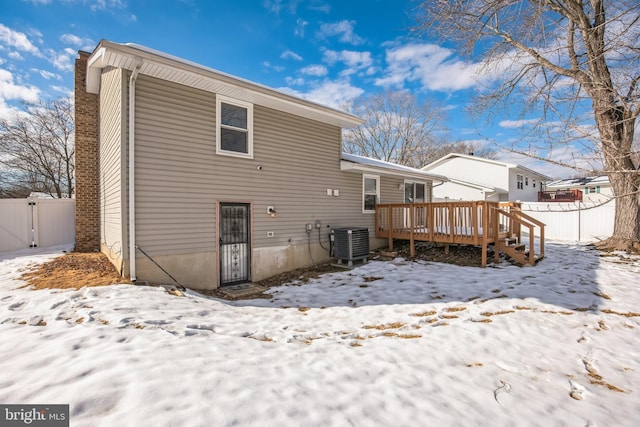 snow covered house featuring central AC and a deck