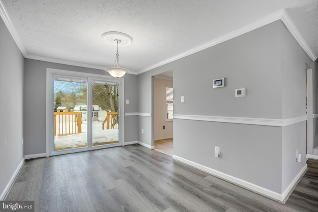 unfurnished dining area with wood-type flooring, a textured ceiling, and ornamental molding