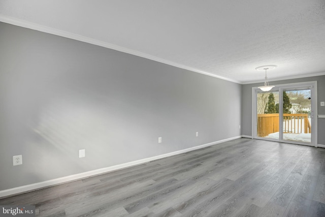 empty room featuring hardwood / wood-style floors, a textured ceiling, and ornamental molding