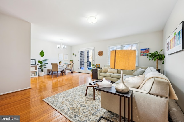 living room featuring wood-type flooring, french doors, and a notable chandelier