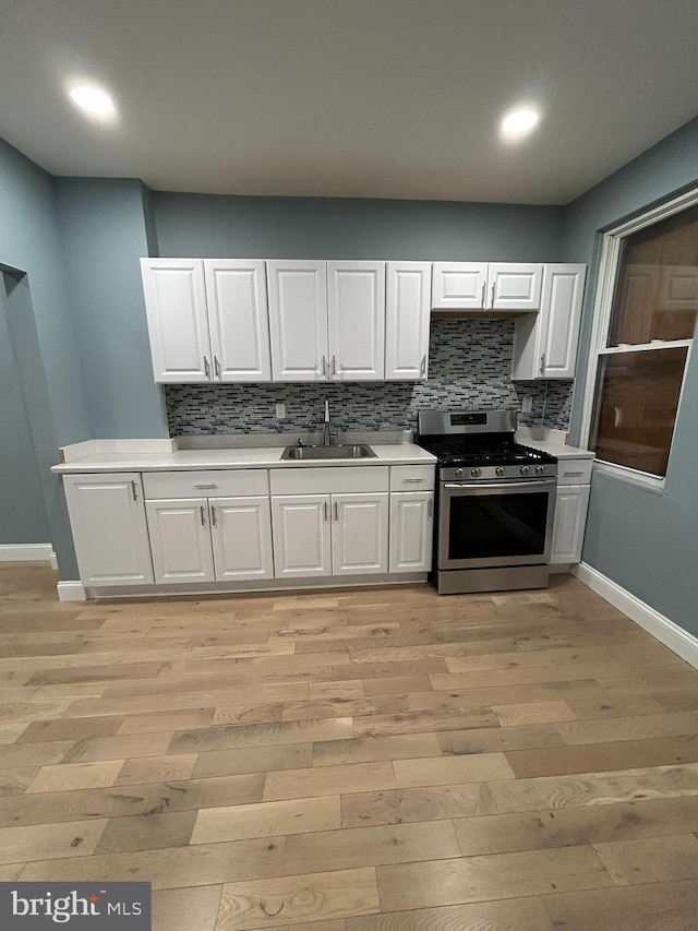 kitchen with sink, light hardwood / wood-style floors, white cabinetry, and stainless steel range oven