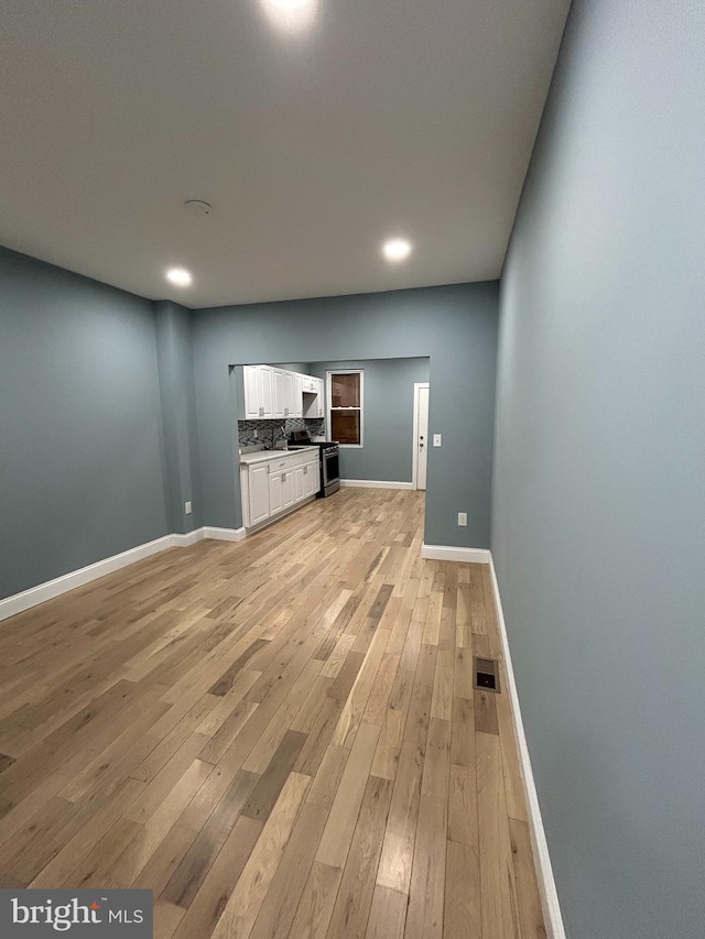 unfurnished living room featuring light wood-type flooring and sink