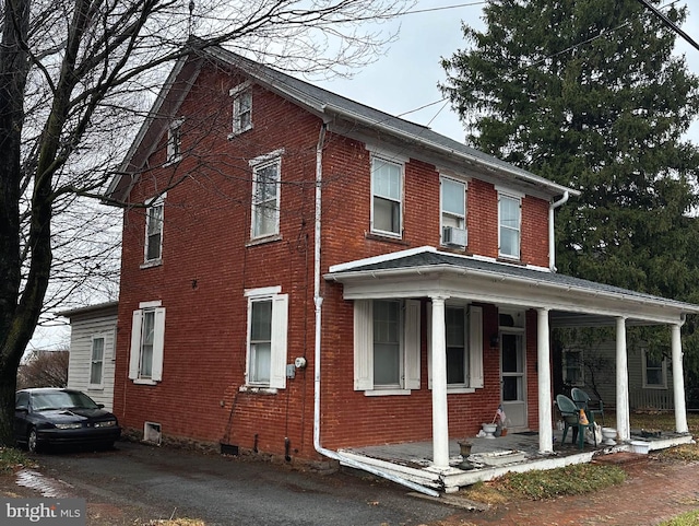 view of side of property with cooling unit, a porch, crawl space, and brick siding