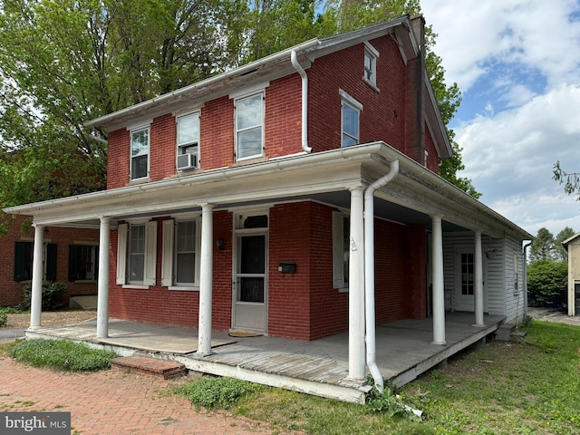 view of front of property featuring cooling unit, brick siding, and covered porch