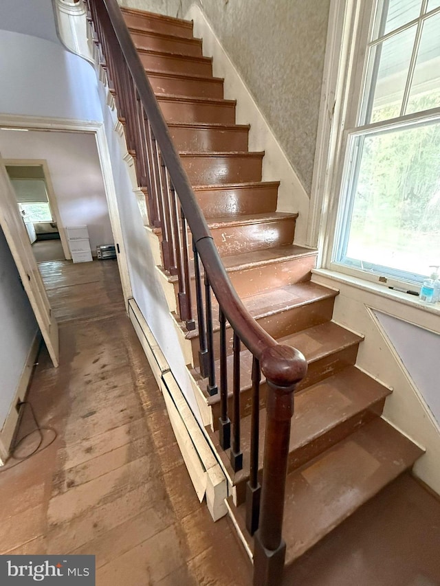 stairway featuring a wealth of natural light, a baseboard heating unit, and hardwood / wood-style flooring