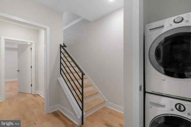 laundry room featuring stacked washer and clothes dryer and light wood-type flooring