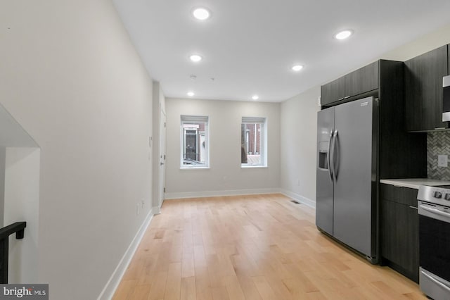 kitchen with backsplash, stainless steel appliances, and light hardwood / wood-style flooring