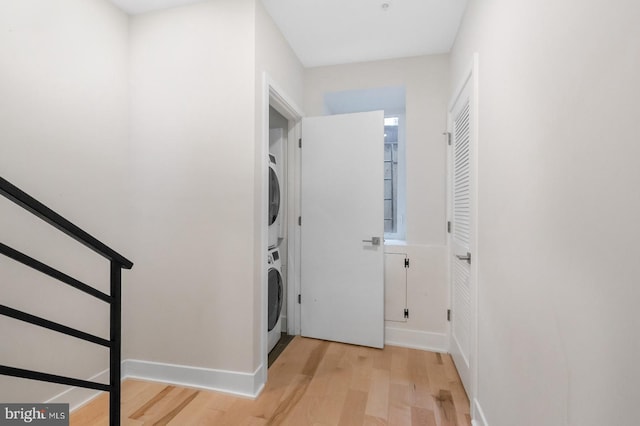 laundry room with stacked washer / drying machine and light hardwood / wood-style floors