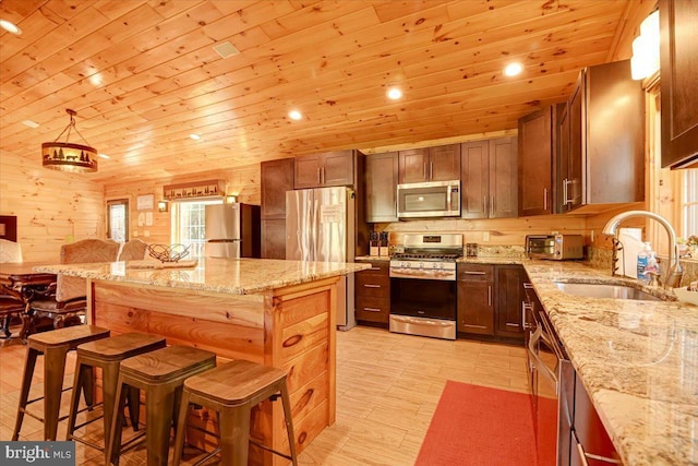 kitchen with sink, stainless steel appliances, a kitchen breakfast bar, light stone counters, and wood ceiling