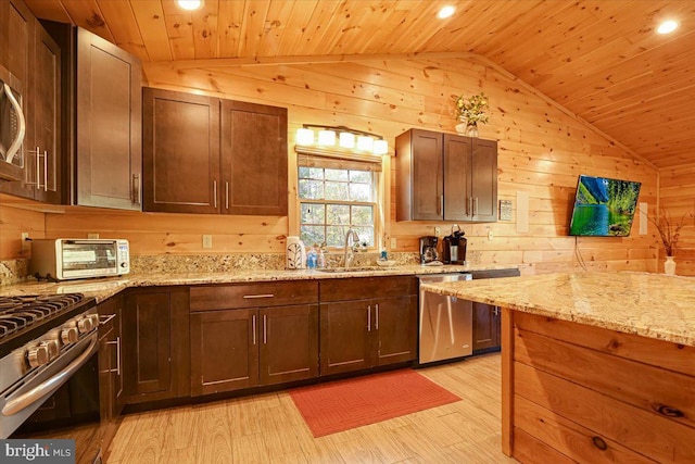 kitchen with lofted ceiling, sink, wooden walls, appliances with stainless steel finishes, and wood ceiling