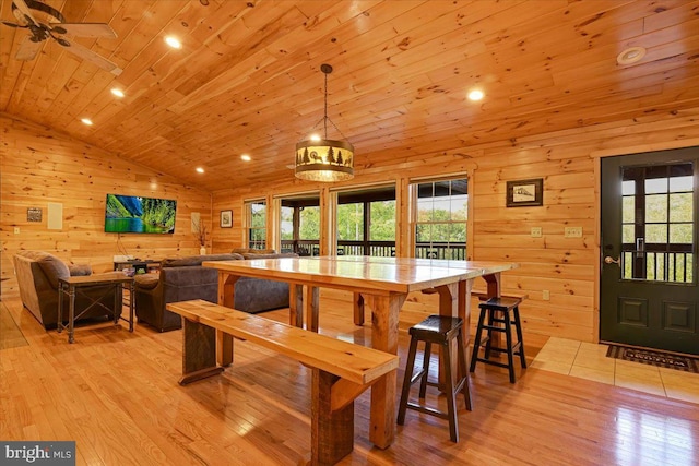 dining area with light hardwood / wood-style flooring, a wealth of natural light, wooden ceiling, and wood walls