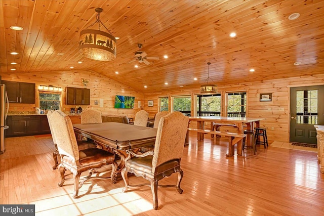 dining space with wood walls, wood ceiling, vaulted ceiling, and light hardwood / wood-style floors