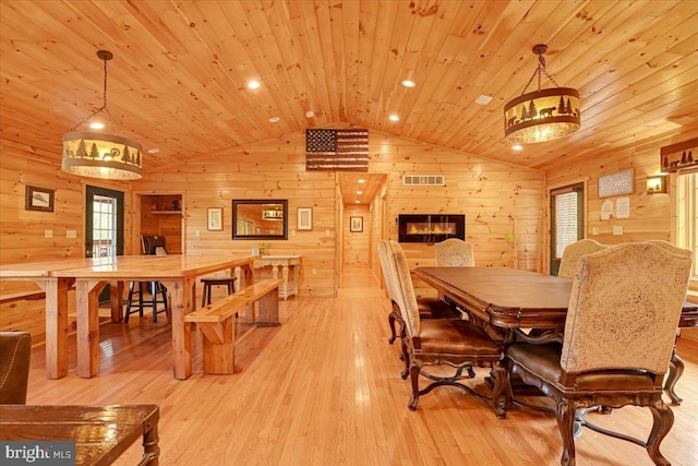 dining space with wood ceiling, wood walls, light hardwood / wood-style floors, and lofted ceiling