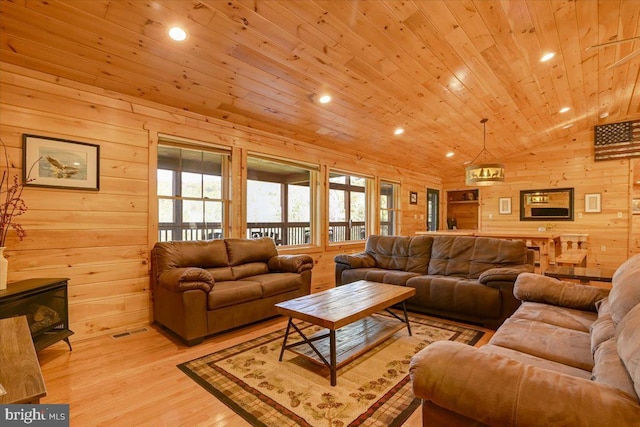 living room featuring a wood stove, light hardwood / wood-style flooring, vaulted ceiling, wooden walls, and wood ceiling