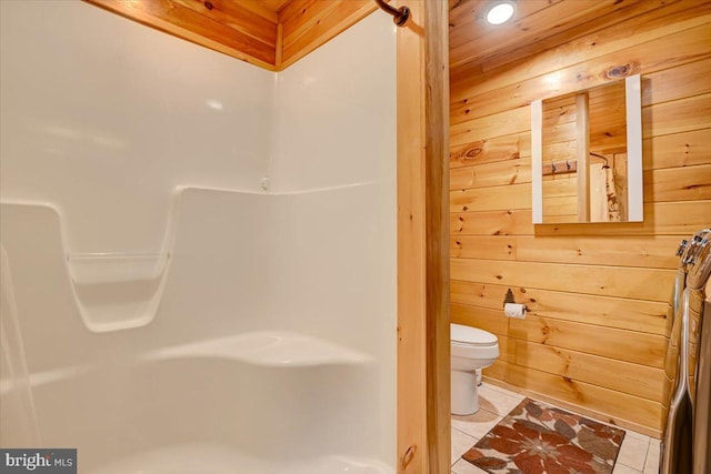 bathroom featuring tile patterned floors, wood walls, and toilet