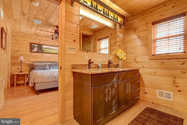 bathroom featuring vanity, wood walls, wooden ceiling, hardwood / wood-style flooring, and ceiling fan