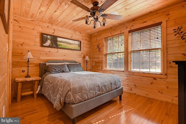 bedroom featuring wooden walls, hardwood / wood-style floors, ceiling fan, and wood ceiling