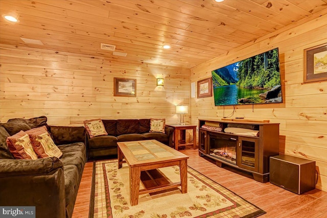 living room featuring wood walls, light hardwood / wood-style floors, and wooden ceiling