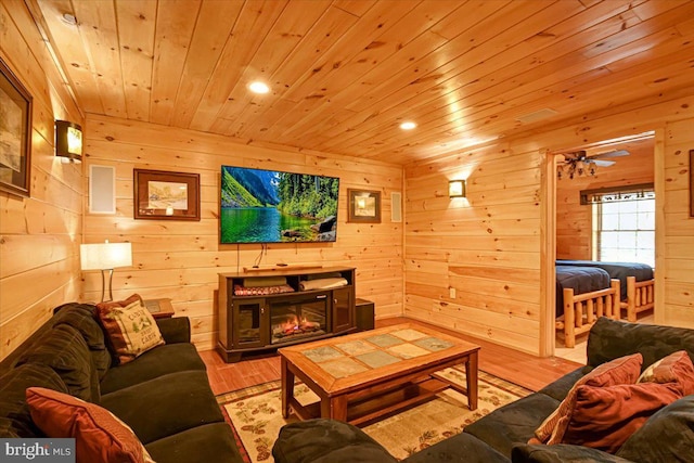 living room featuring wood walls, ceiling fan, wooden ceiling, and light wood-type flooring