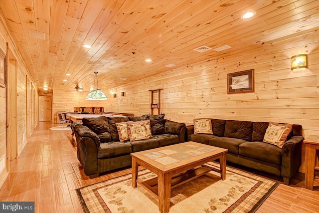 living room with light wood-type flooring, wooden ceiling, and wood walls