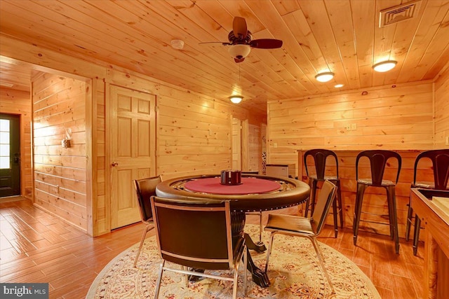 dining area with wood ceiling, wood walls, and light hardwood / wood-style floors