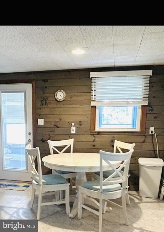 dining space featuring wood walls and concrete floors