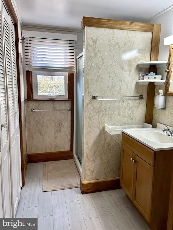 bathroom featuring crown molding, a shower with door, and vanity