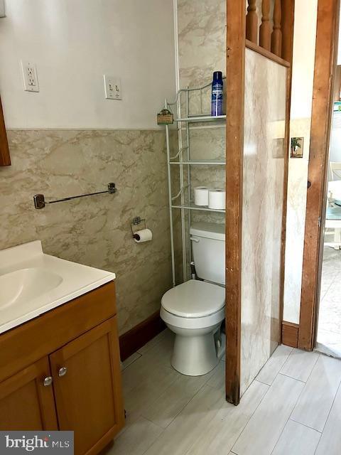 bathroom with vanity, tile walls, and toilet