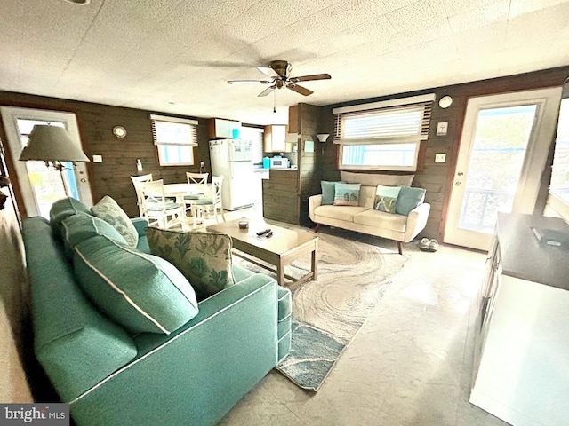 living room featuring ceiling fan and wooden walls