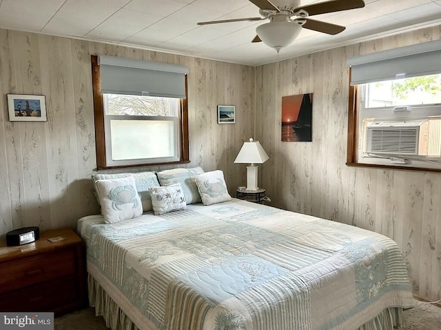 bedroom featuring ceiling fan, cooling unit, and wood walls