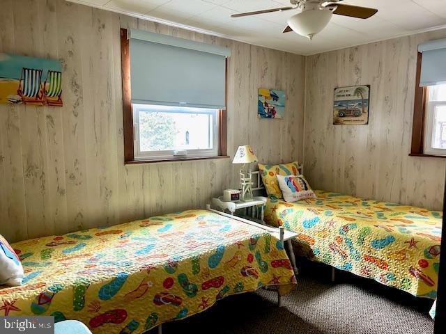 bedroom with ceiling fan and wooden walls